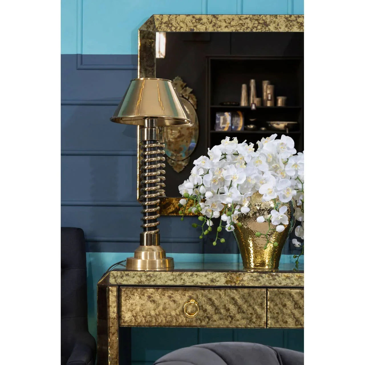 Gold mirrored console table with metallic lamp and white orchid arrangement in vase