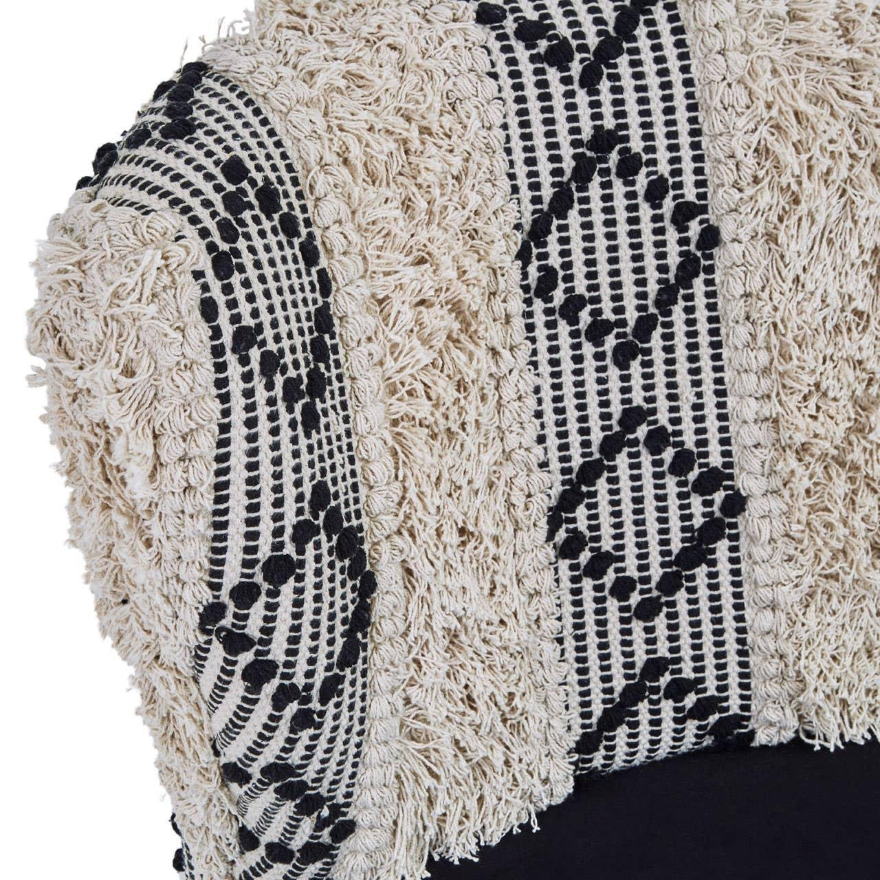 Textured cream and black patterned cushion cover close-up with woven fringe detail