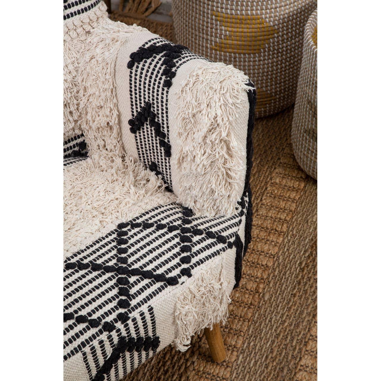 Textured fabric armchair with black and cream geometric pattern on woven jute rug