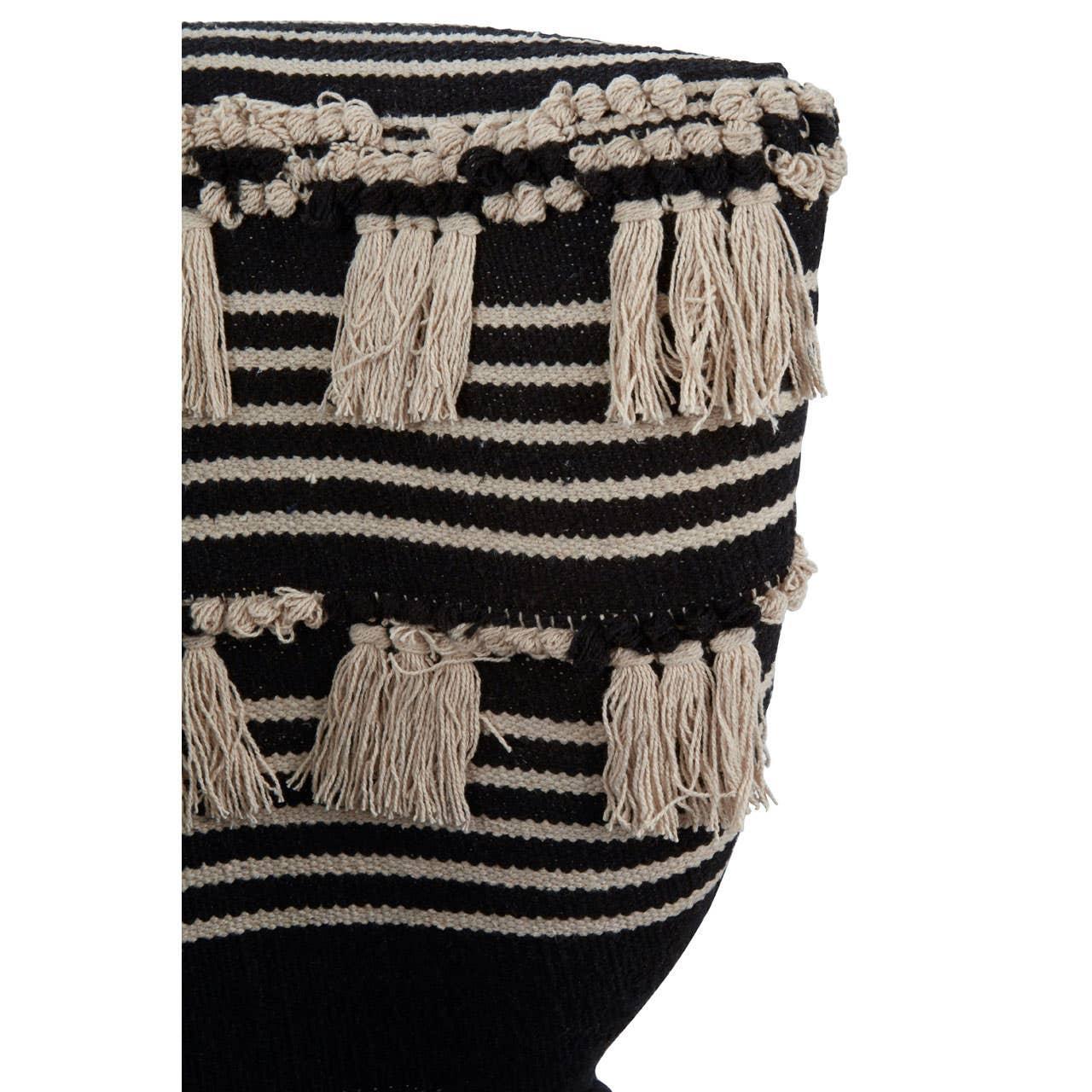 Striped woven cushion with black and beige tassel detail, closeup of textured fabric
