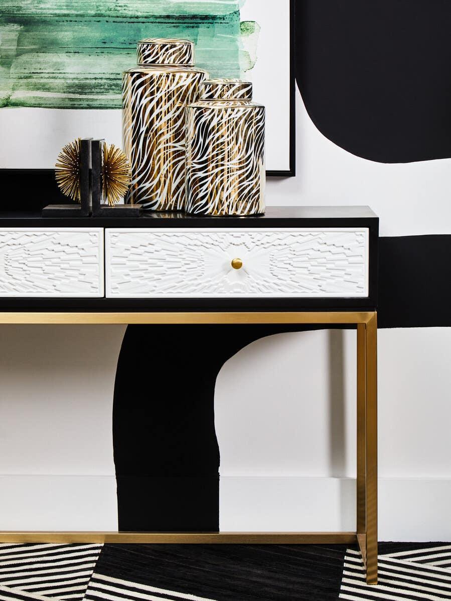 Gold and black console table with white textured drawers and zebra print vases