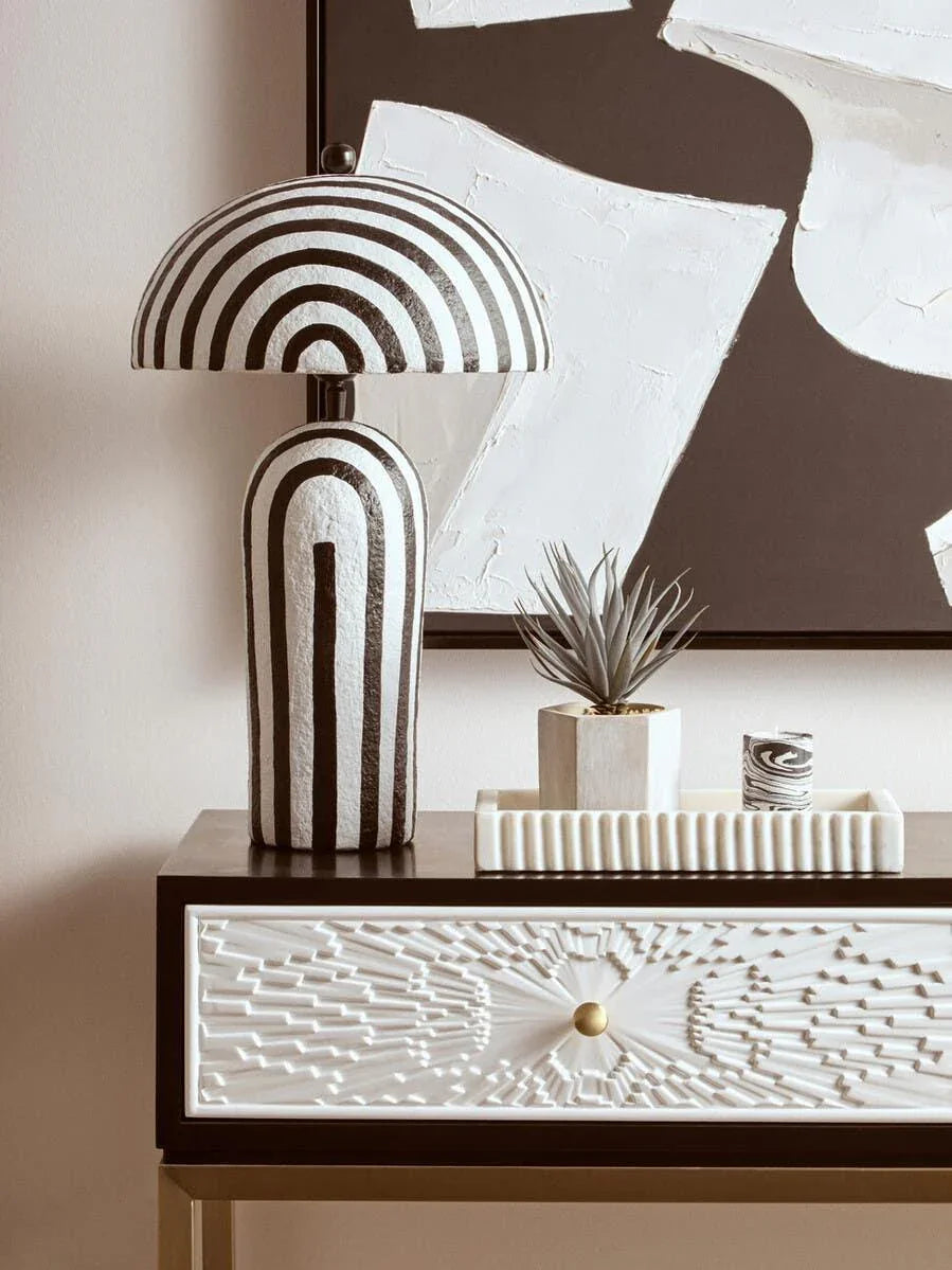 Black and white striped table lamp on textured drawer cabinet with decor accents