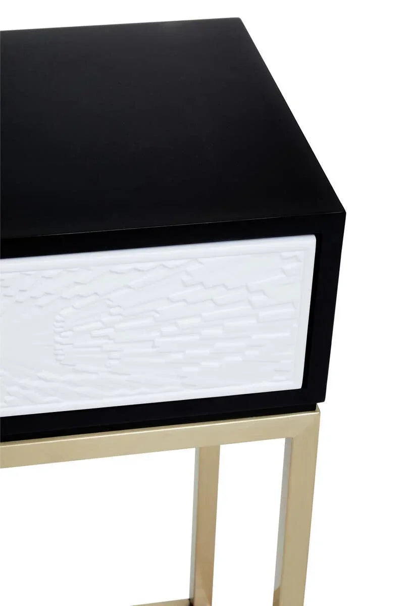 Black bedside table with gold legs and white textured drawer front, close-up view