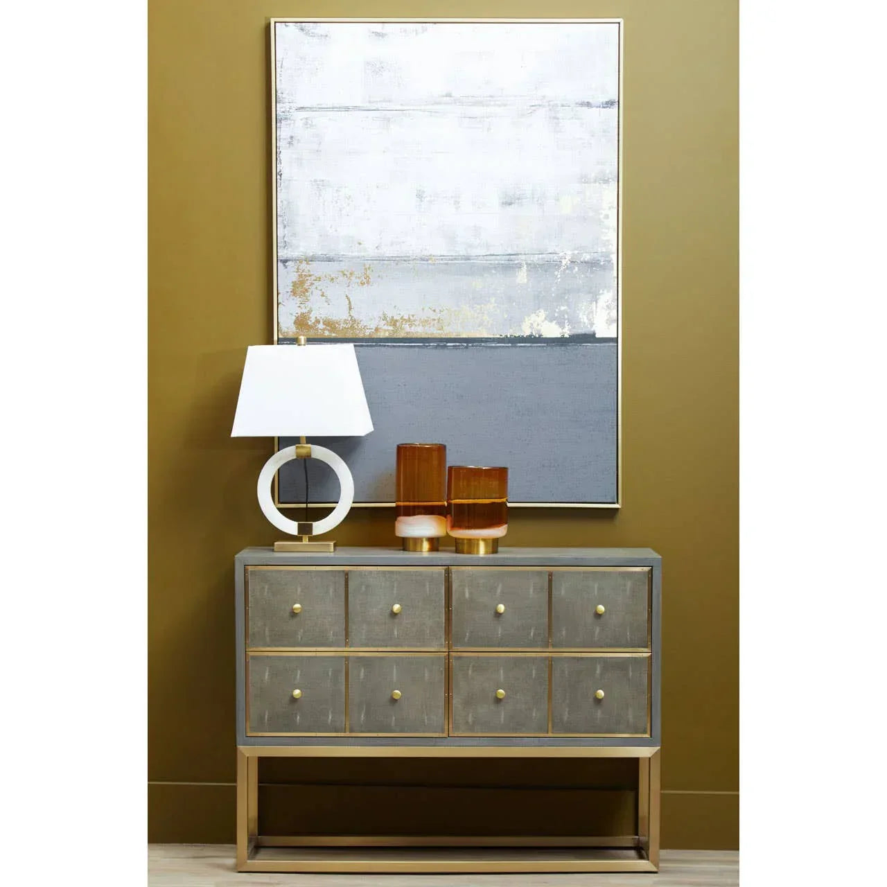 Modern sideboard with gold accents, table lamp, amber glass vases, and abstract wall art