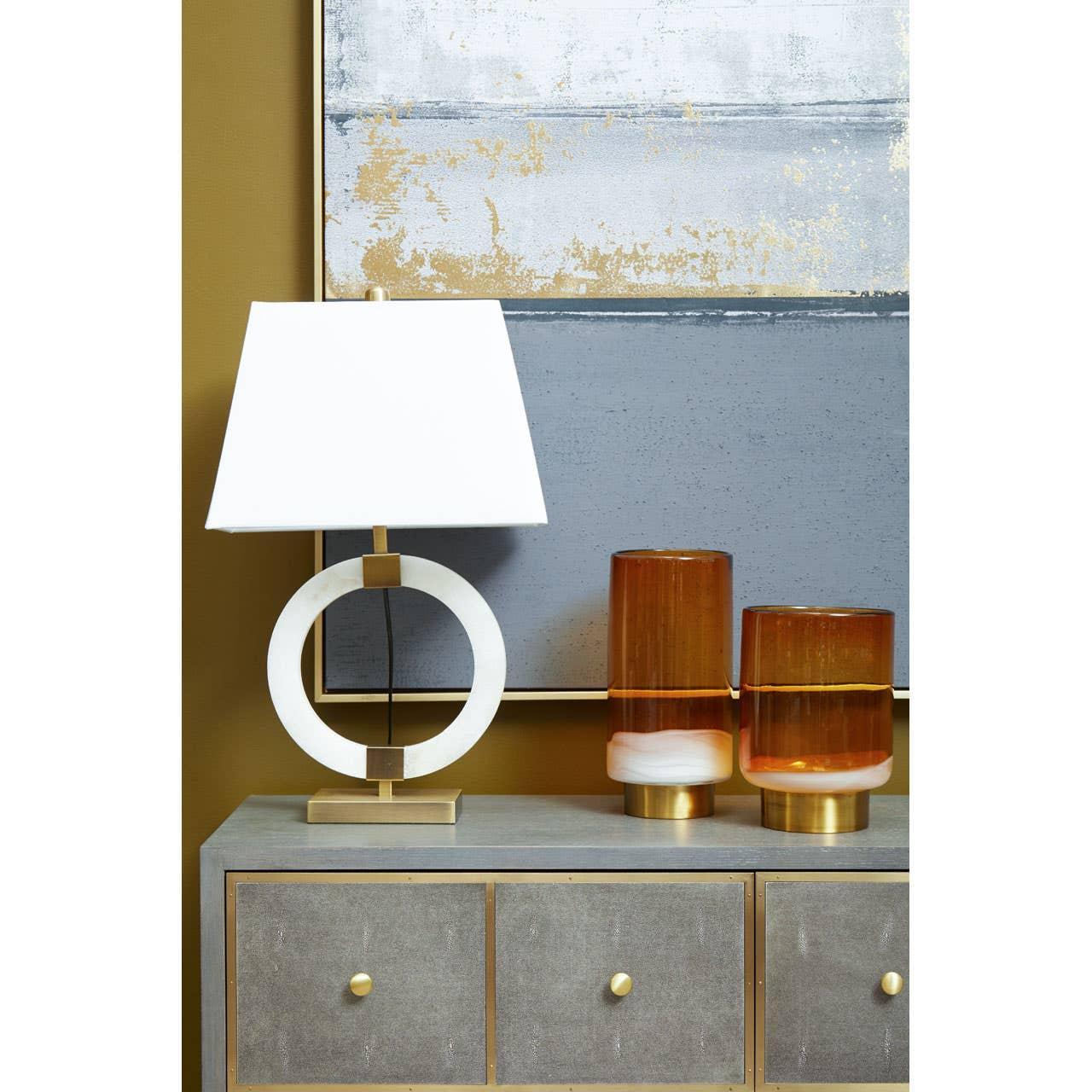 Modern table lamp with white circular base and two amber glass vases on grey sideboard