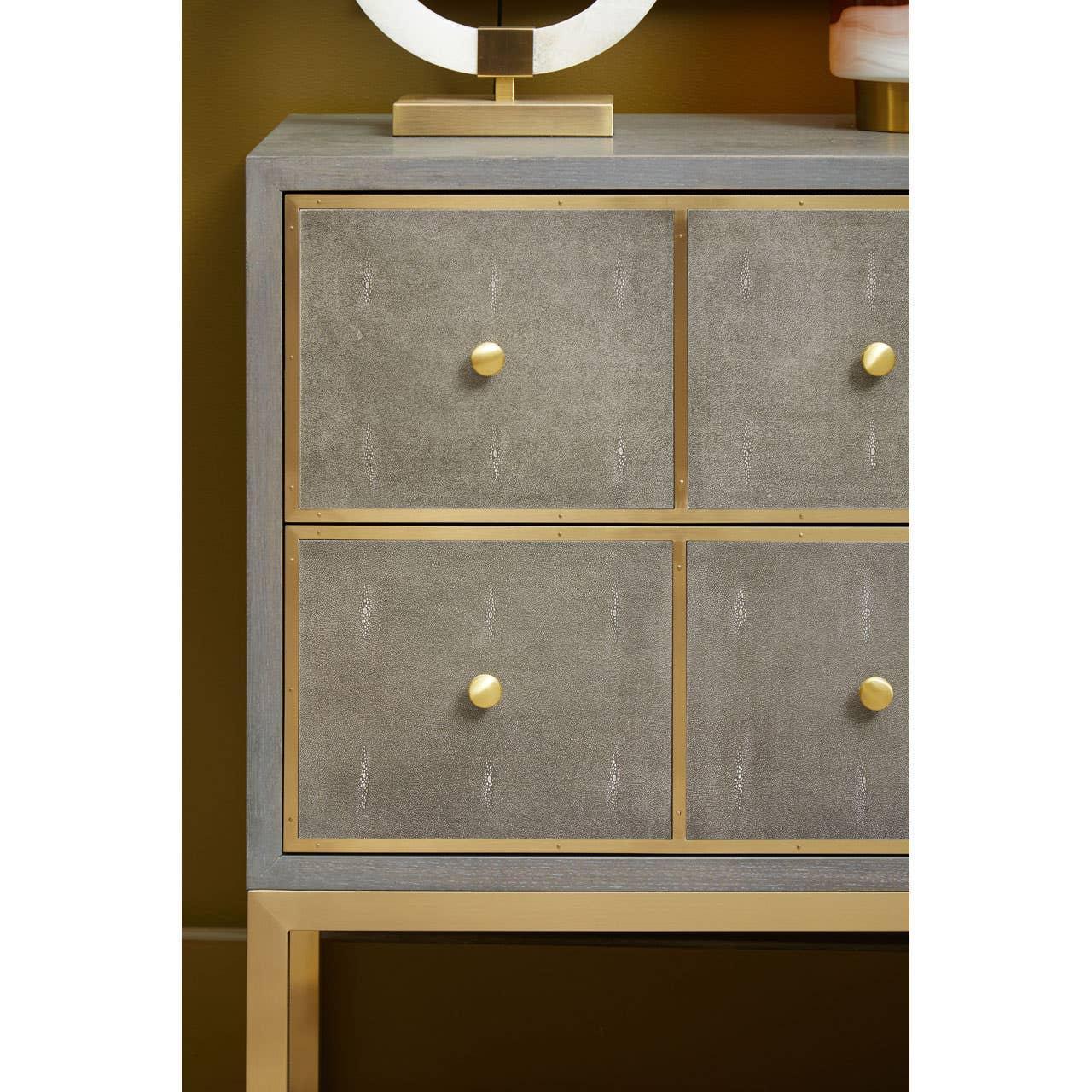 Grey and gold sideboard with four textured drawers and brass knobs