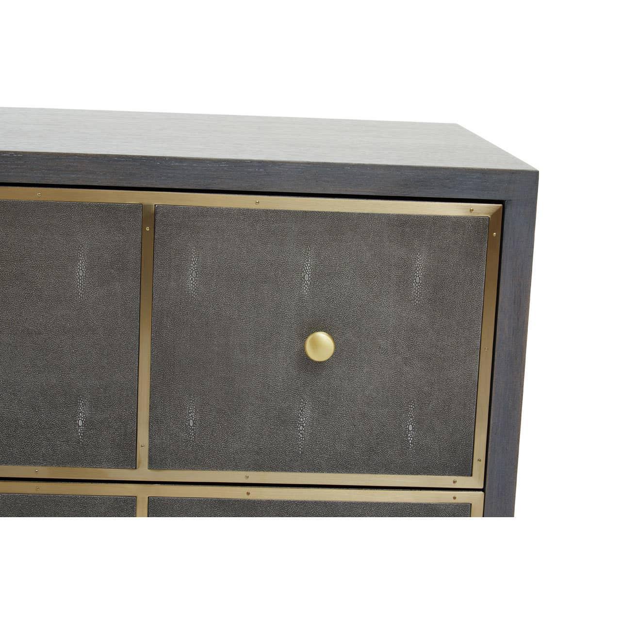 Closeup of chest of drawers with textured grey panel, gold knob and brass trim