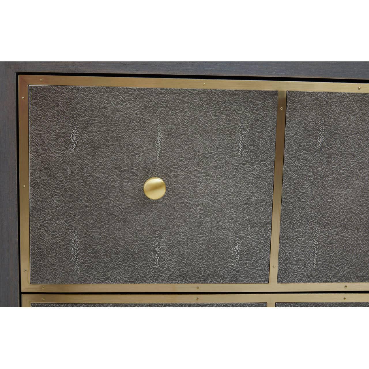 Close-up of textured dresser drawer with gold metal frame and round brass handle
