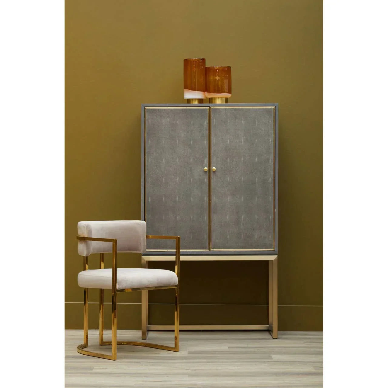 Modern velvet dining chair with gold frame beside grey cabinet in contemporary room setting