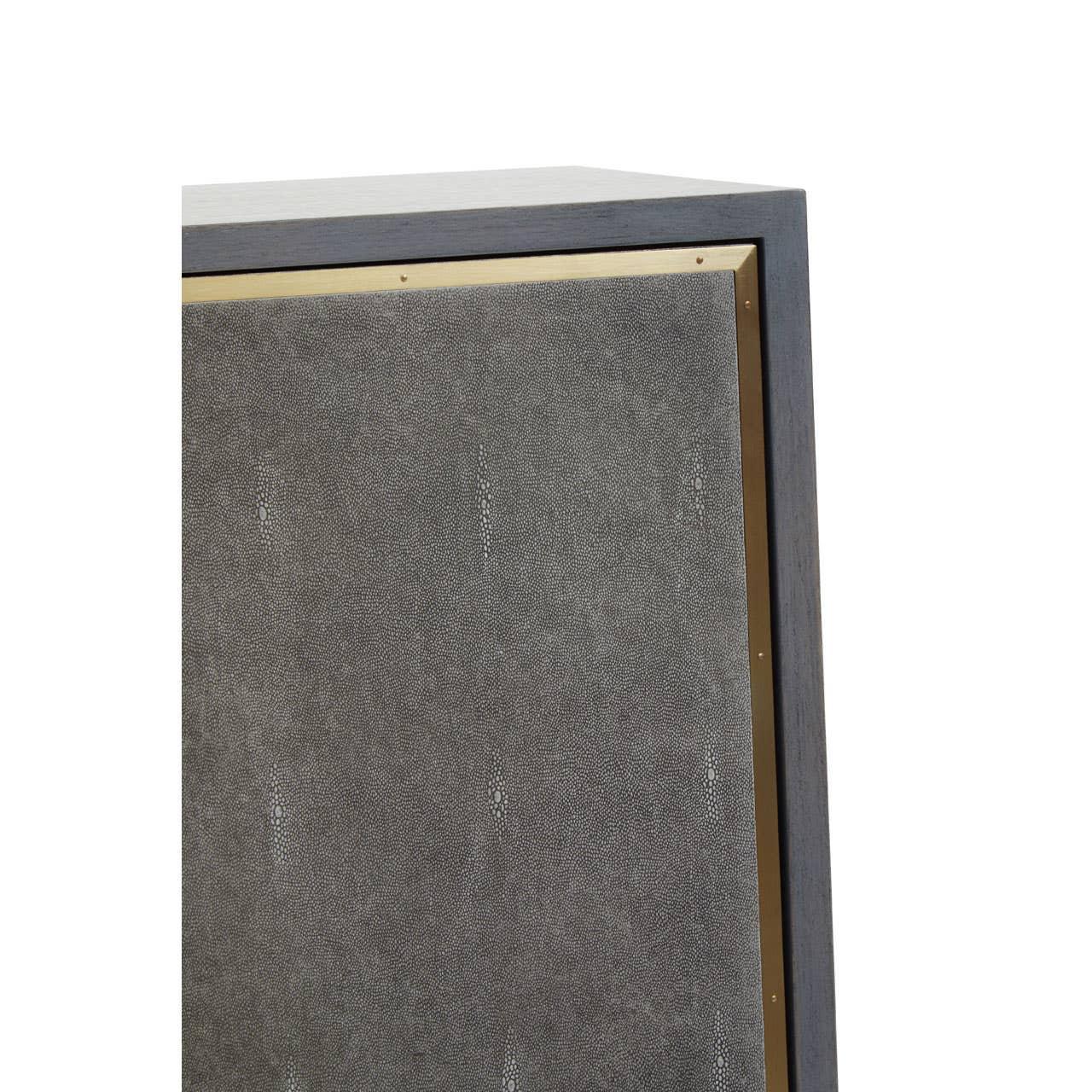 Closeup of textured grey cabinet door with brass trim and dark wood frame