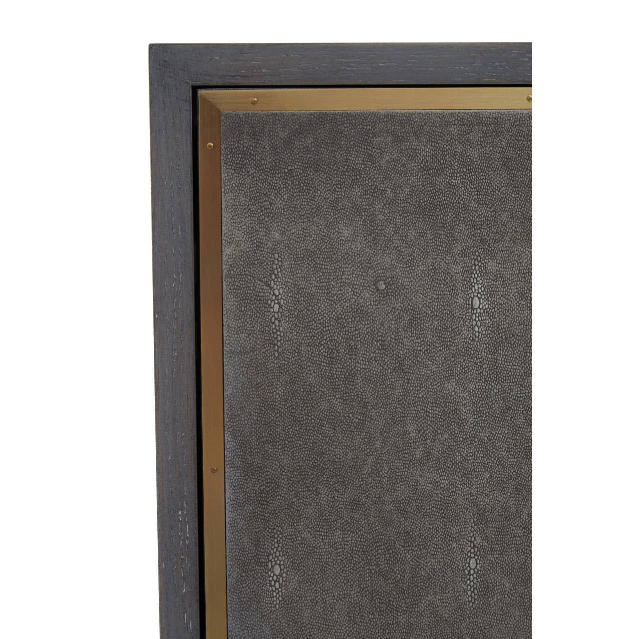Close up of textured cabinet door with dark wood frame and brass trim detail