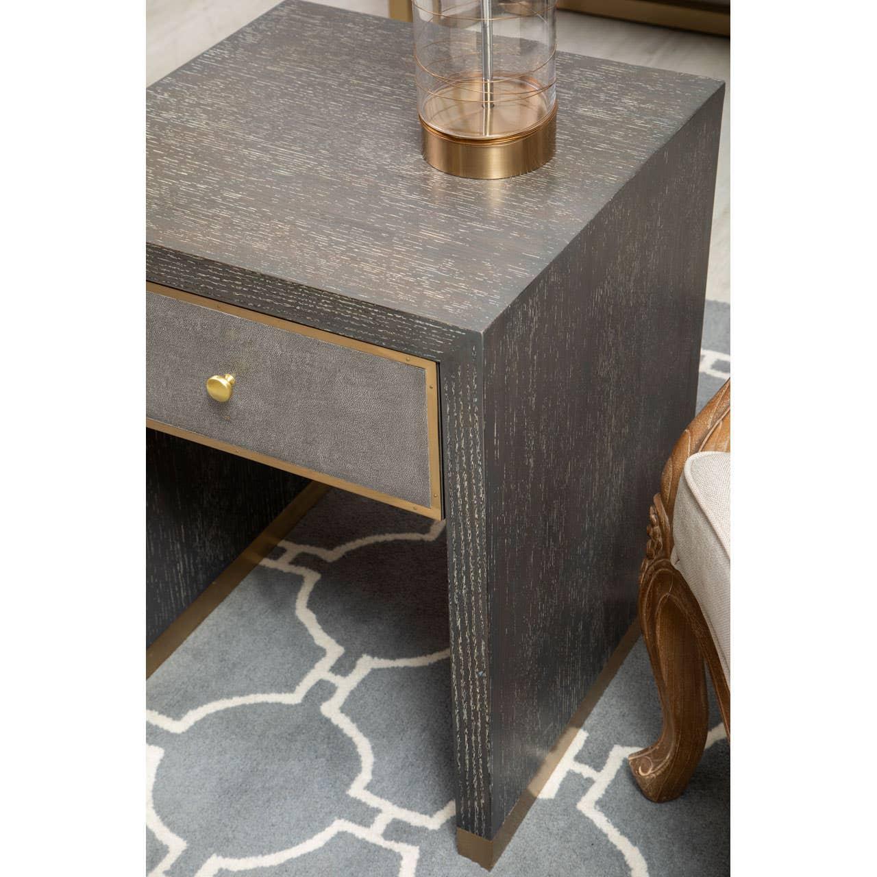Modern dark wood side table with gold trim and single drawer on geometric rug