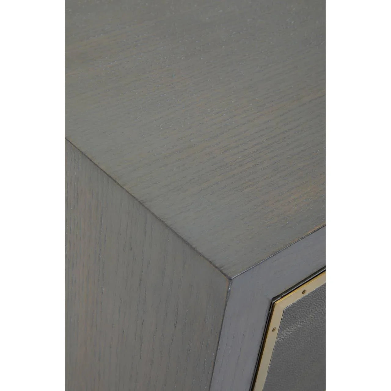Close view of grey wood cabinet corner with brass trim detail