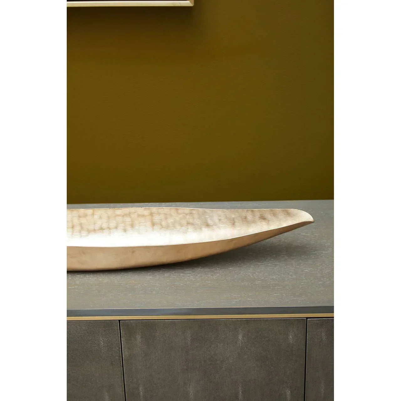Textured beige decorative bowl on grey sideboard against olive wall