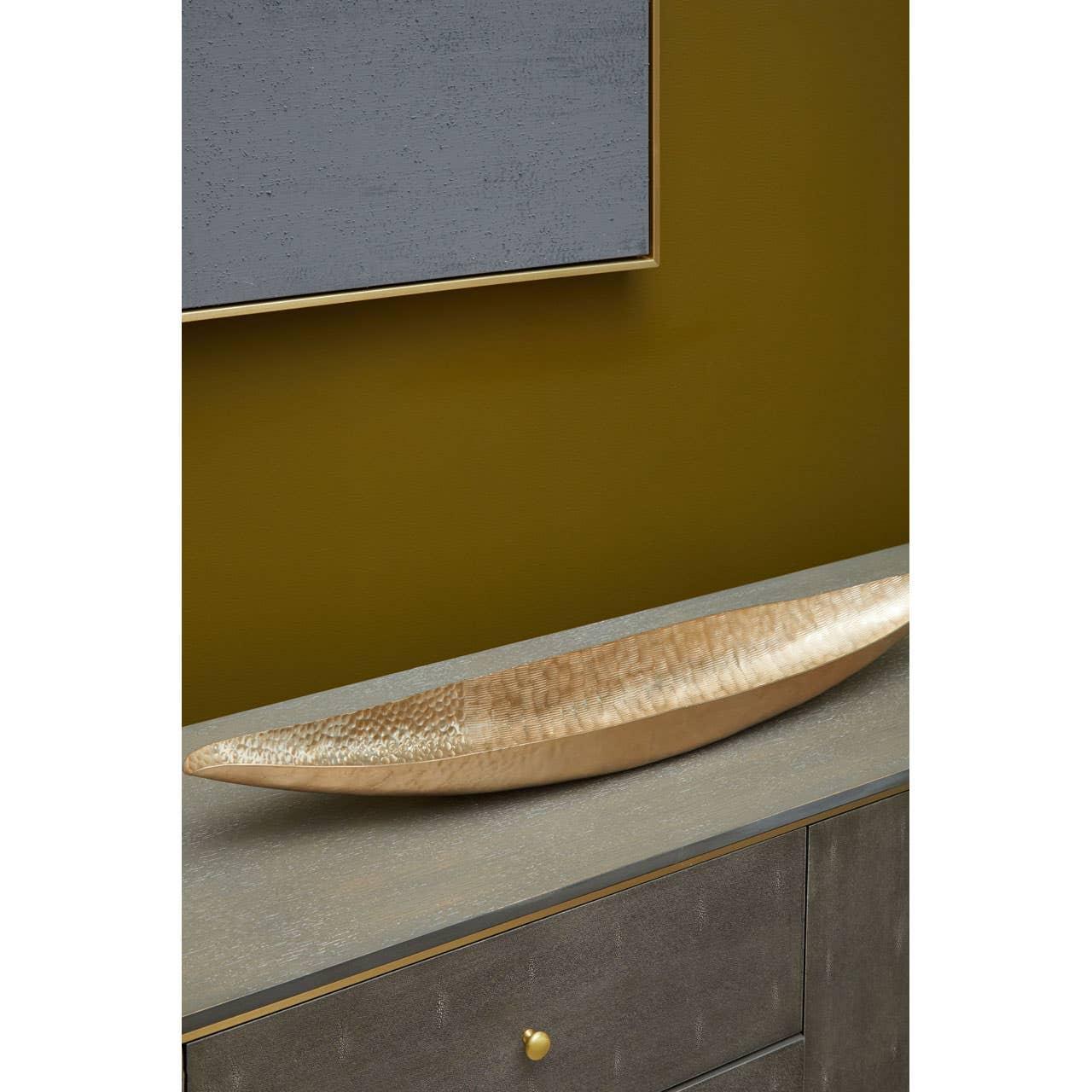 Brushed gold decorative bowl on grey sideboard against mustard wall