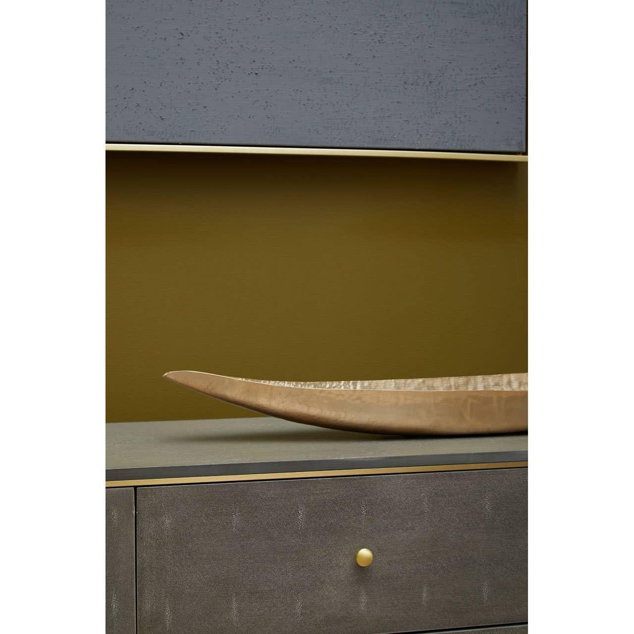 Grey sideboard with gold drawer knob and decorative tray on textured surface