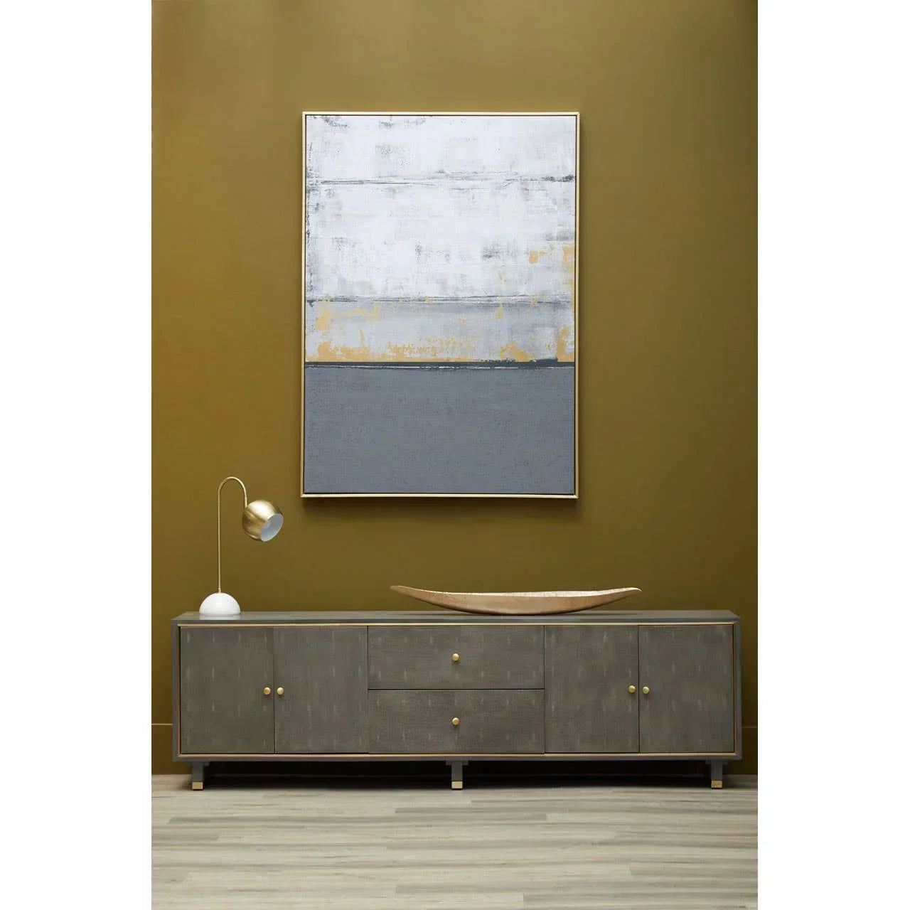 Grey wooden sideboard with gold handles and table lamp against ochre wall