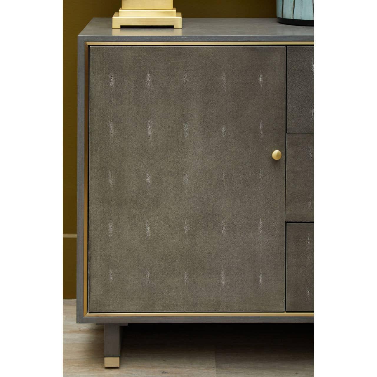 Close-up sideboard cabinet with textured grey door, gold knob, and brass corner accents