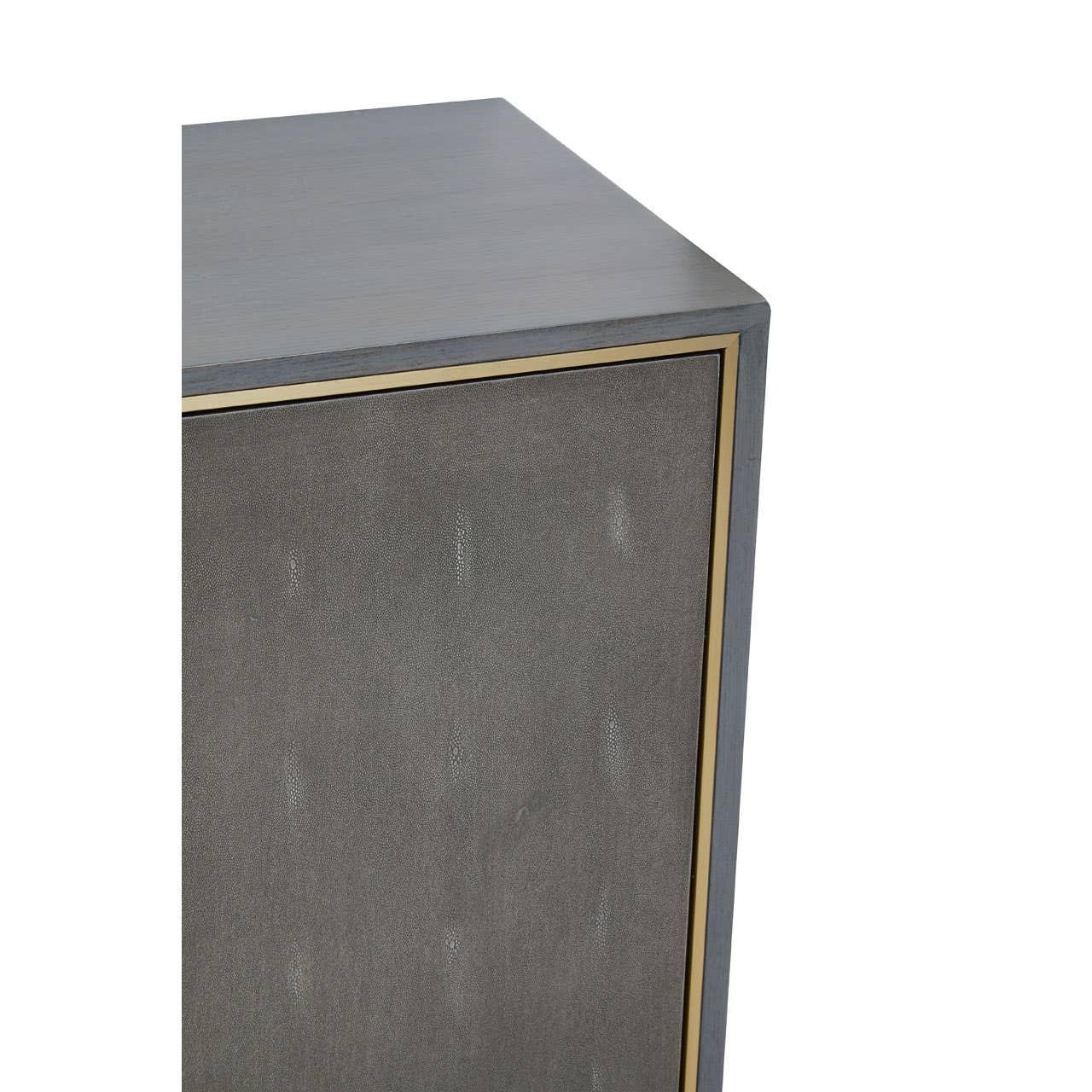 Grey wood cabinet with brass trim corner and textured front panel close-up