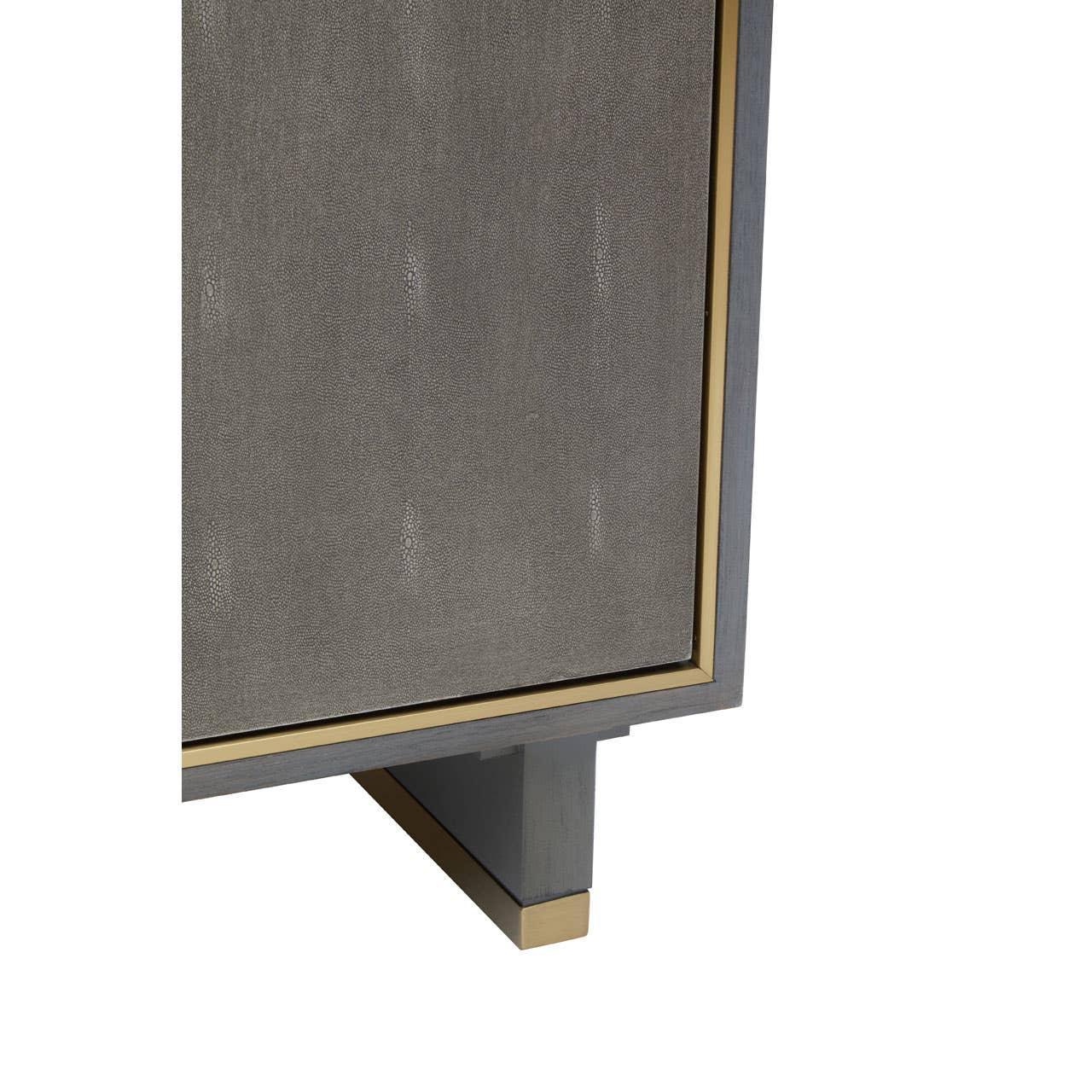 Closeup of grey cabinet with textured finish and gold trim on wooden base