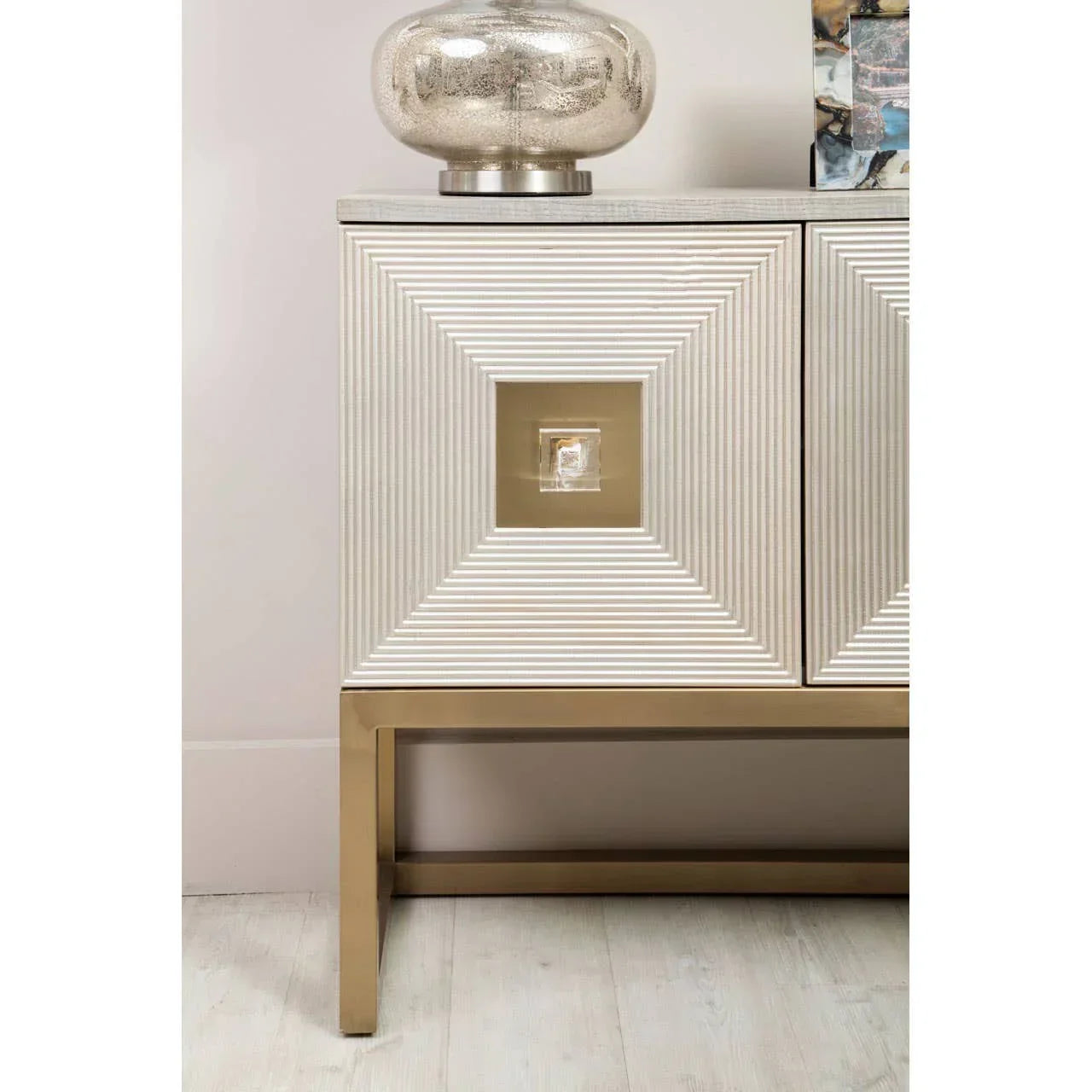 Modern sideboard with gold metal base, textured doors and glass lamp on top