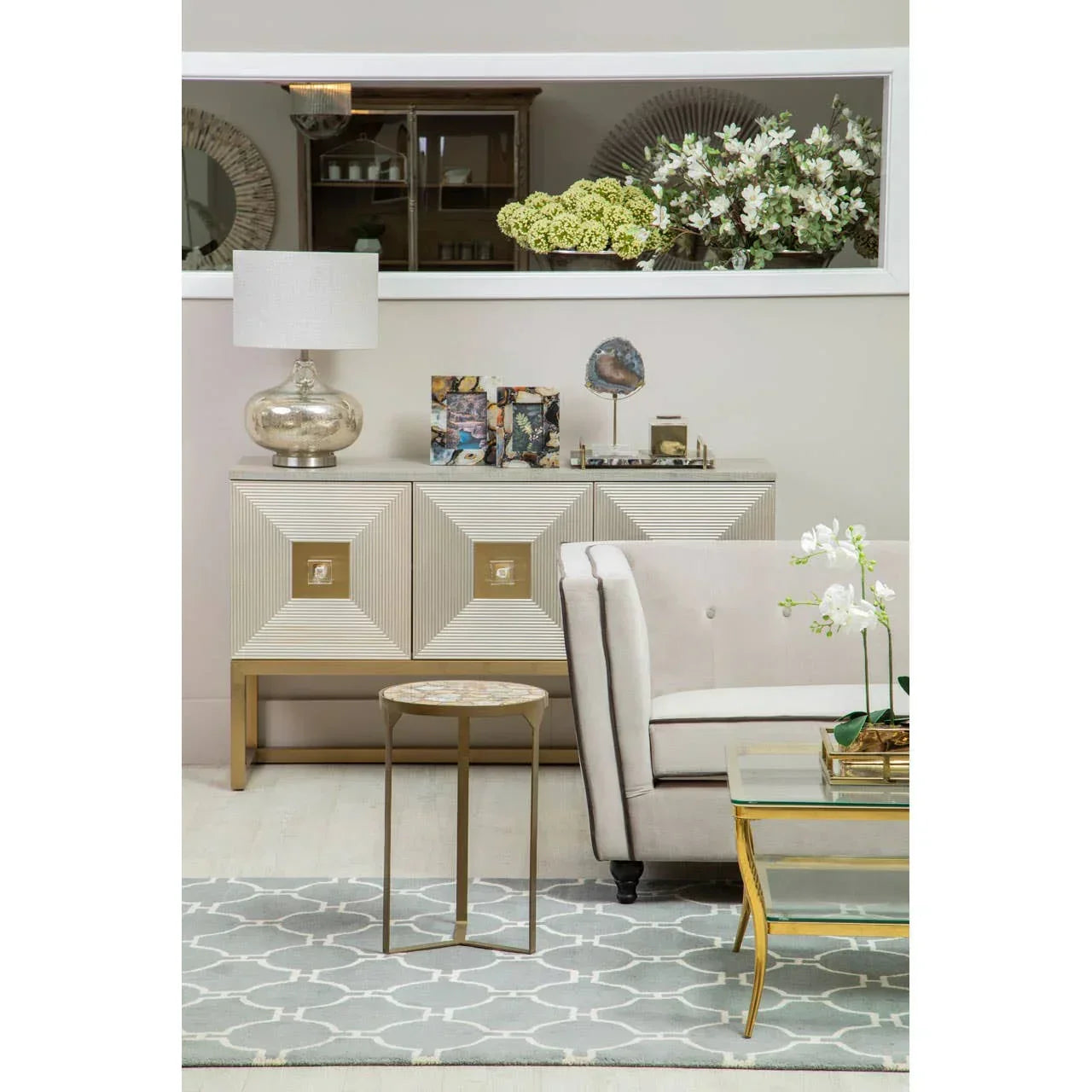 Neutral velvet sofa with gold side table and geometric sideboard in modern living room