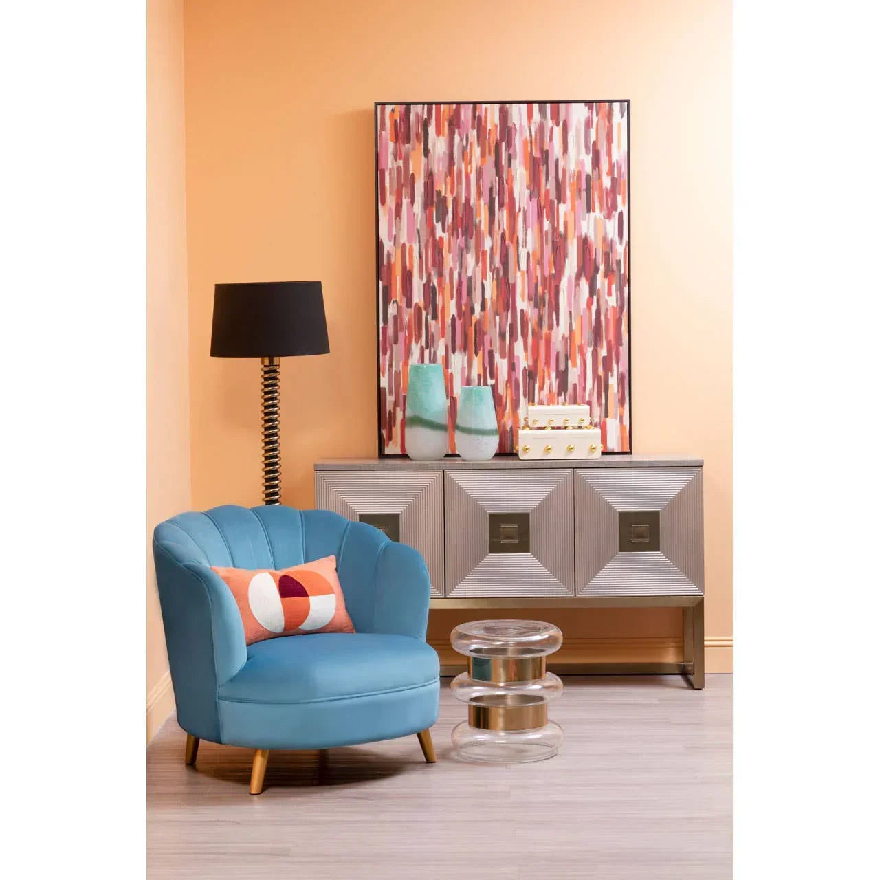Blue accent chair with geometric cushion, modern sideboard, and abstract wall art