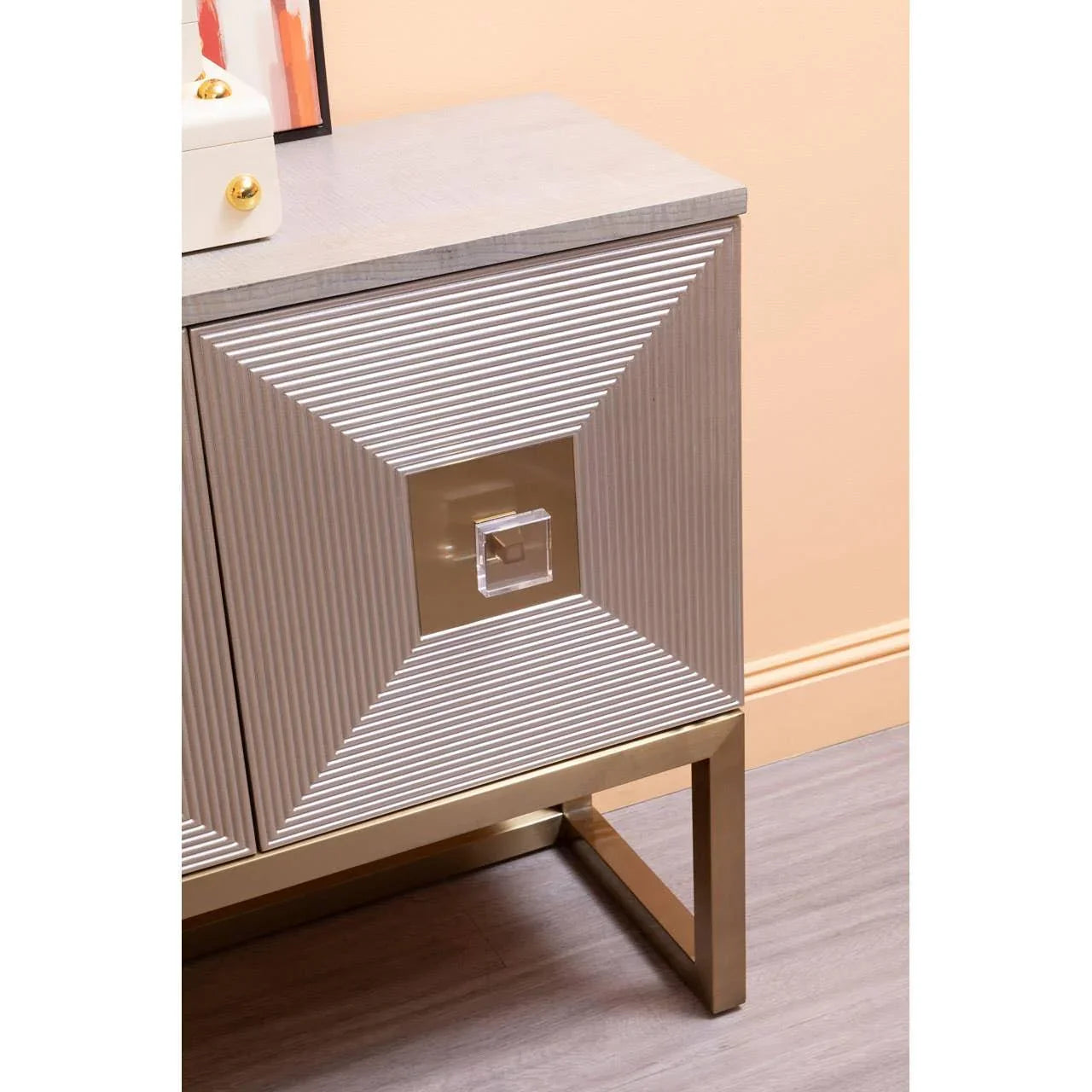 Modern sideboard cabinet with gold metal legs and textured doors in a neutral-toned room