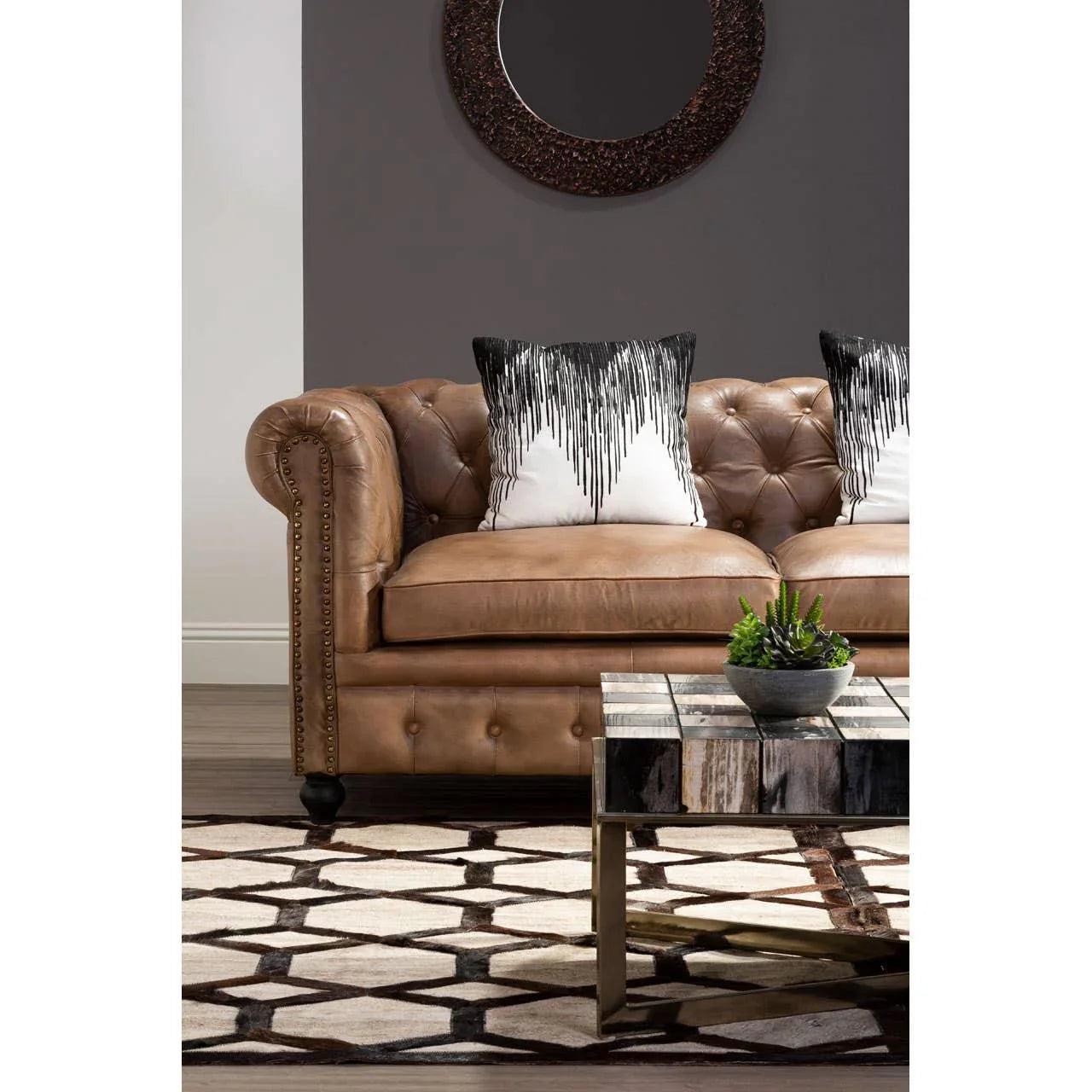 Tan leather sofa with tufted cushions, monochrome pillows, and geometric patterned rug