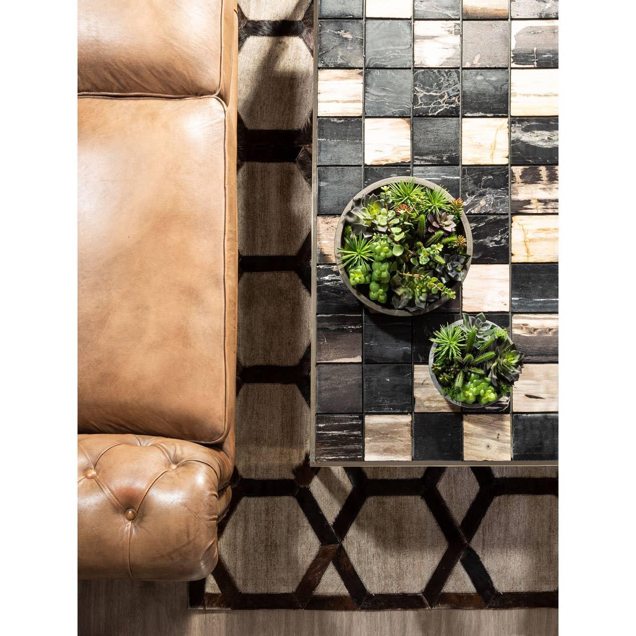 Tan leather sofa beside tiled coffee table with succulents and geometric patterned rug