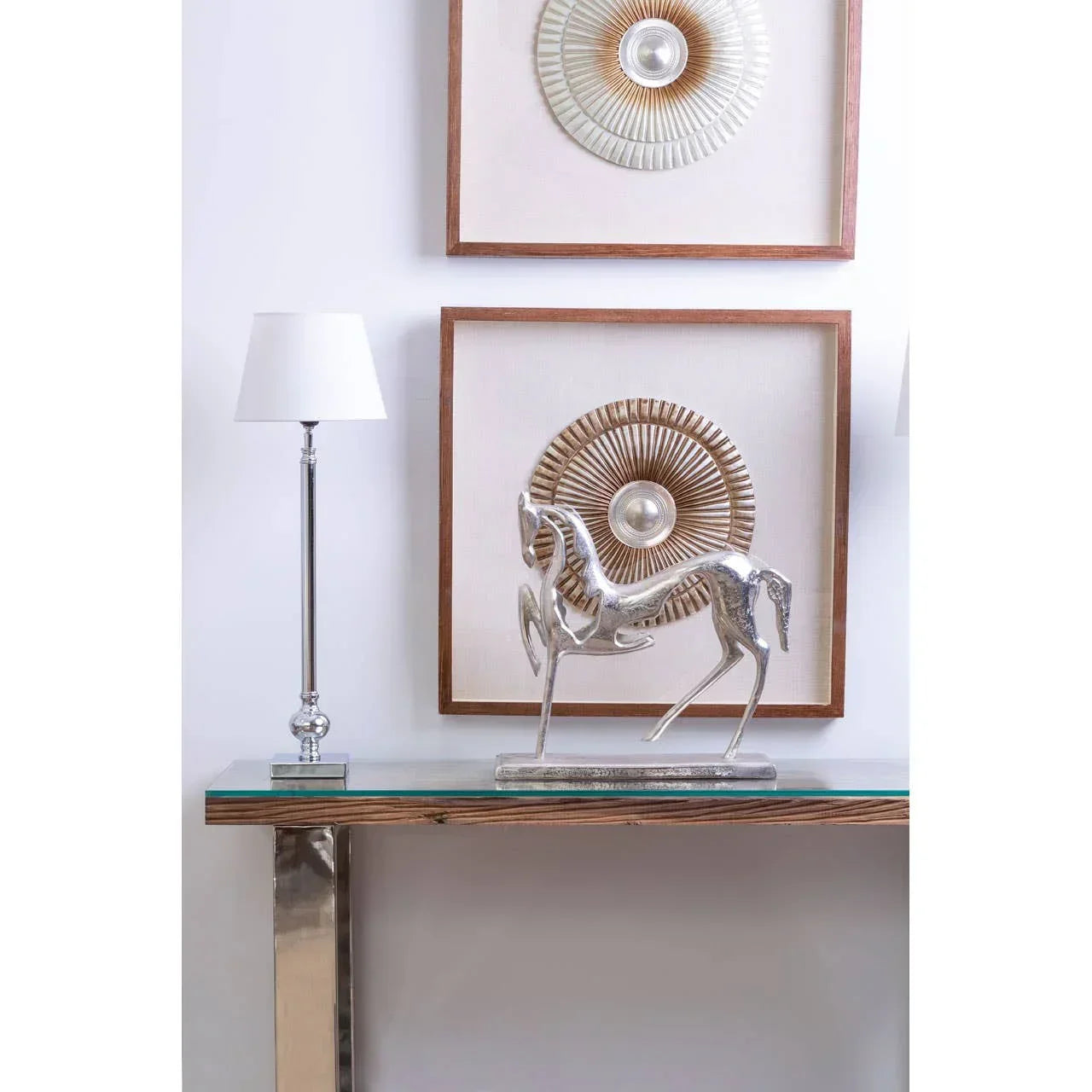 Silver horse ornament on glass console table with chrome lamp and modern wall art decor