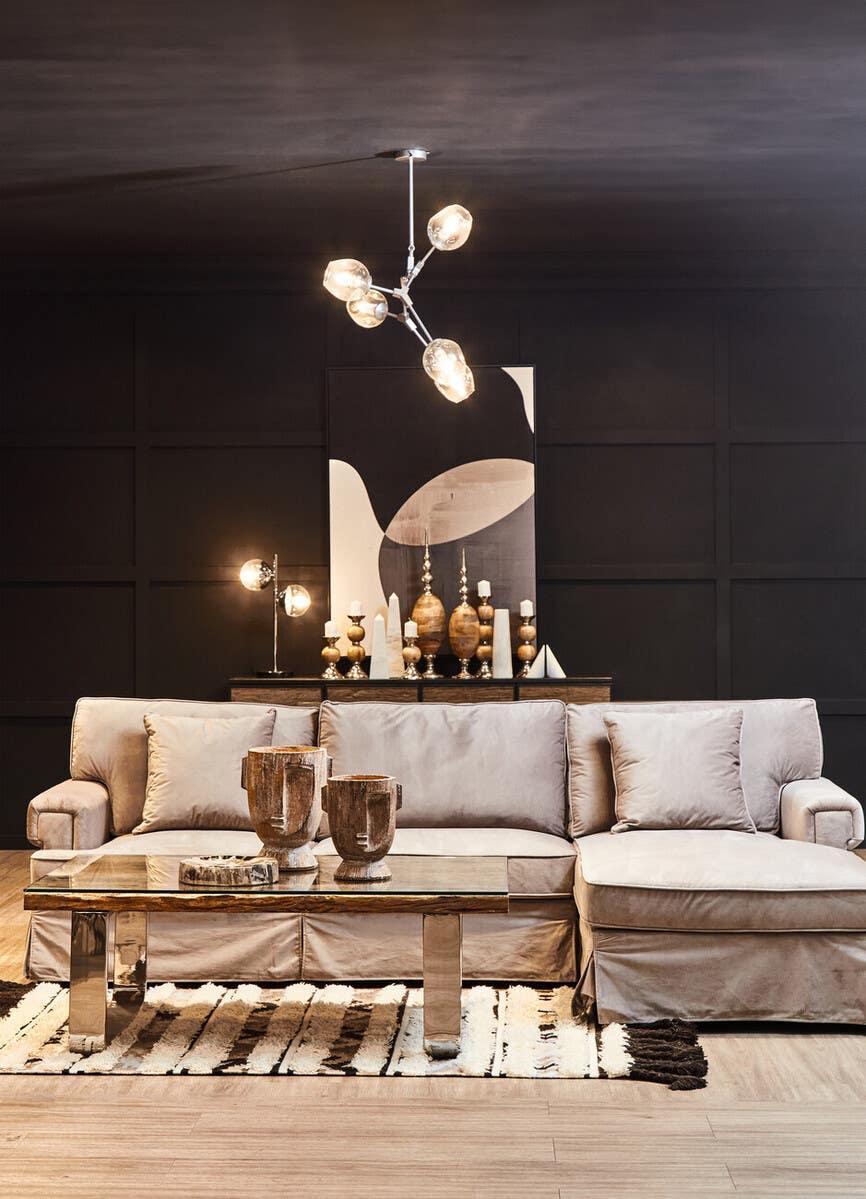 Beige fabric sofa with metal coffee table in modern living room, abstract art on black wall