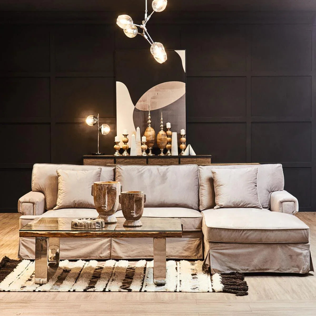 Beige fabric corner sofa with chaise lounge and glass coffee table in modern living room
