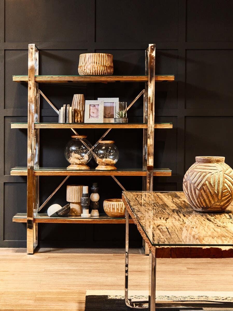 Modern glass and metal shelving unit with wood accents and decorative home accessories