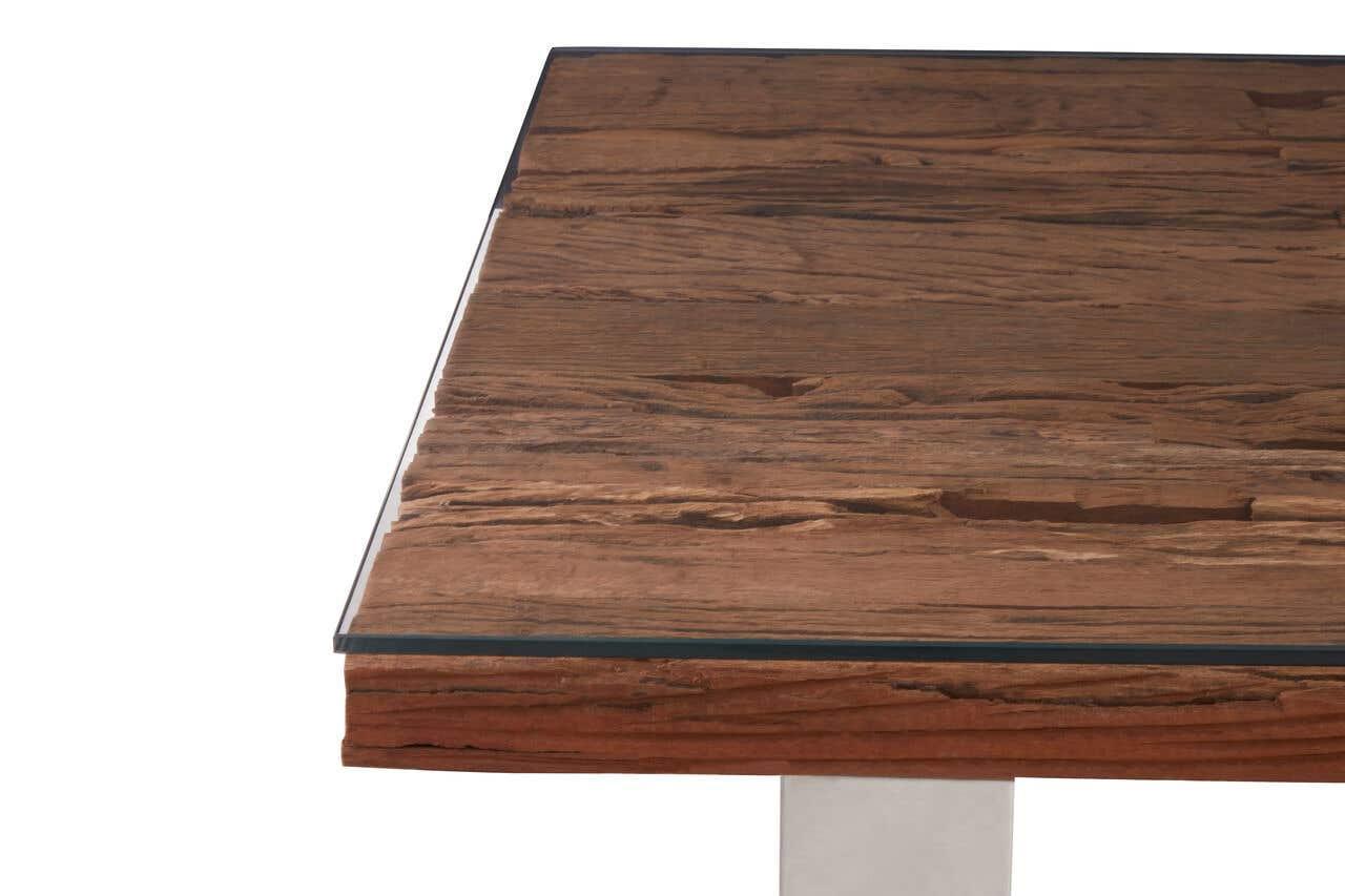 Close-up of wooden dining table with glass top and metal leg