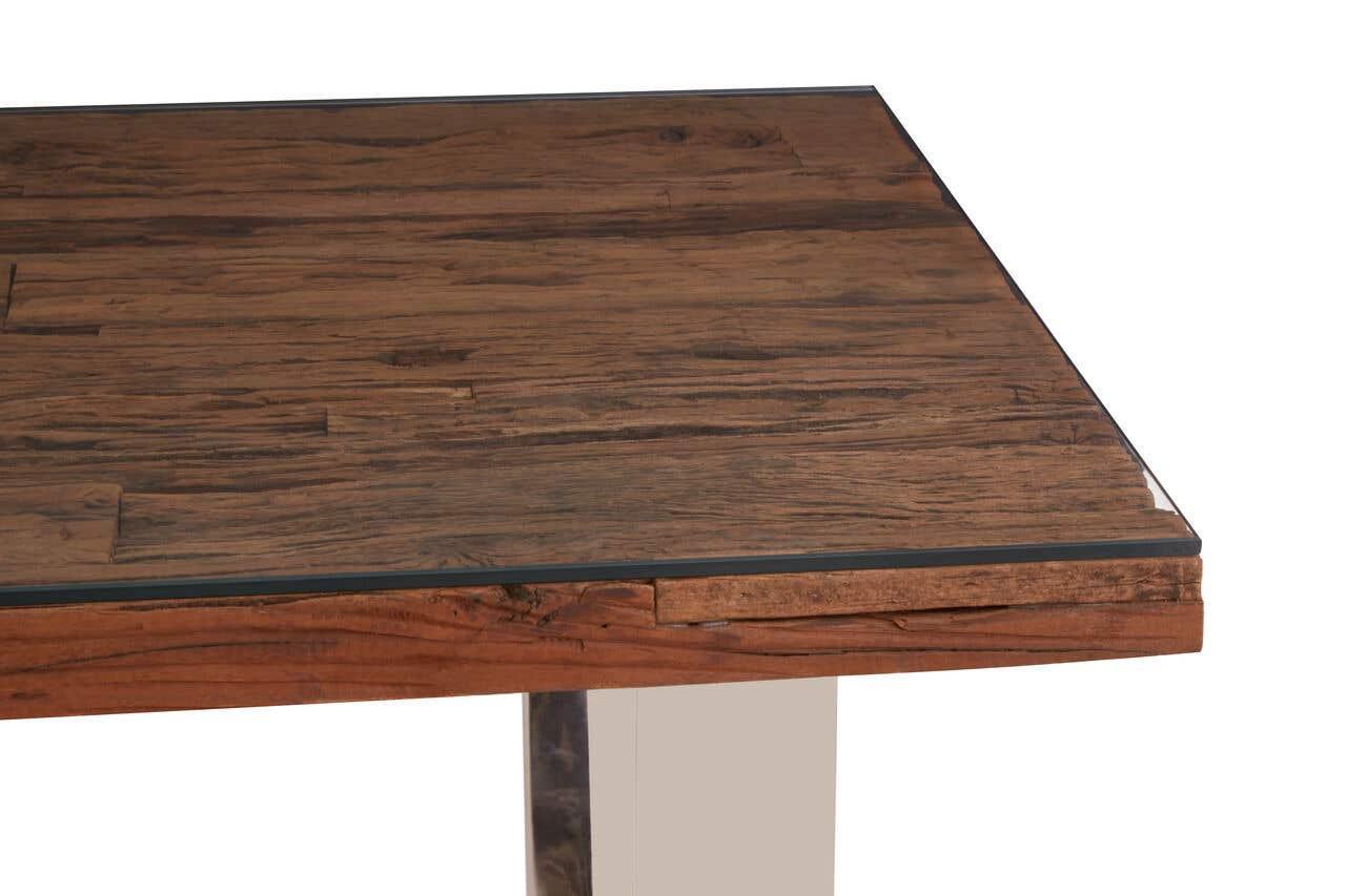 Wood dining table with glass top corner and metal leg close up