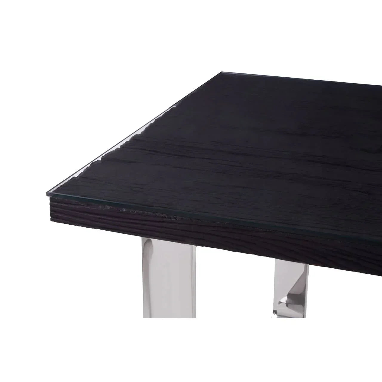 Closeup of dining table with dark wood top, glass overlay, and chrome metal legs