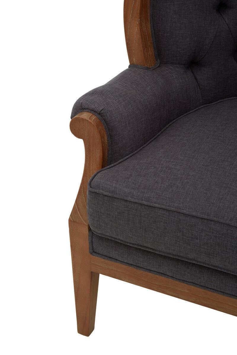 Dark fabric armchair with tufted backrest and wooden arm detail, close-up view