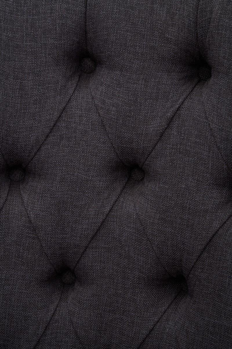 Dark grey upholstered sofa with deep button tufting fabric detail close-up