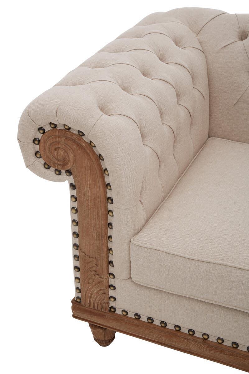 Beige upholstered sofa with deep button tufting and ornate wooden armrest detail
