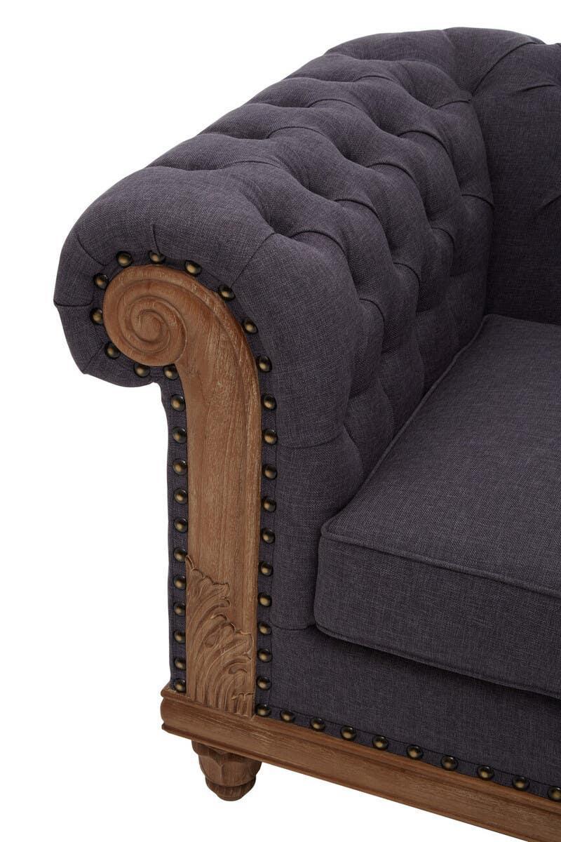 Dark grey fabric sofa arm with button-tufted upholstery and decorative wooden trim