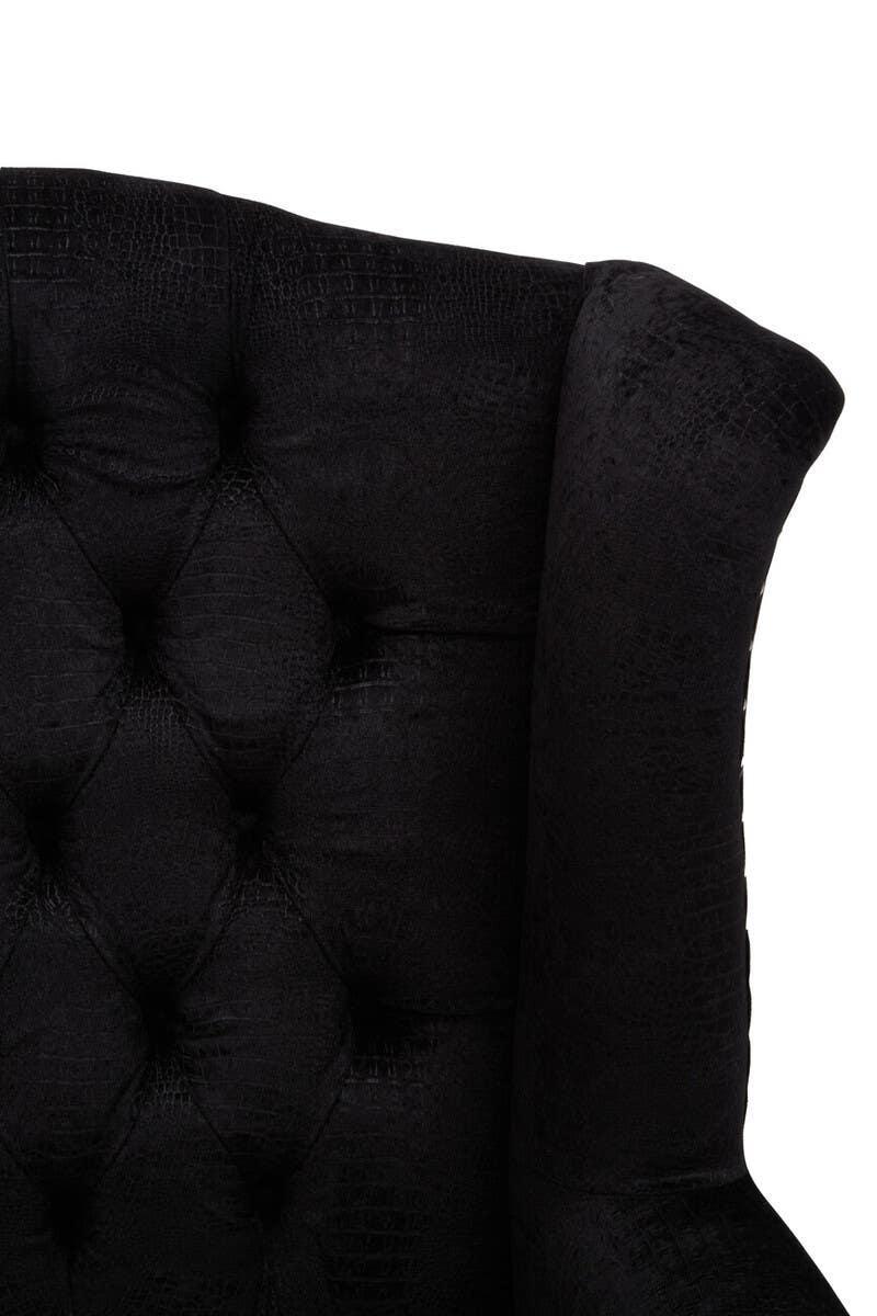 Close-up of black upholstered armchair with textured button-tufted backrest