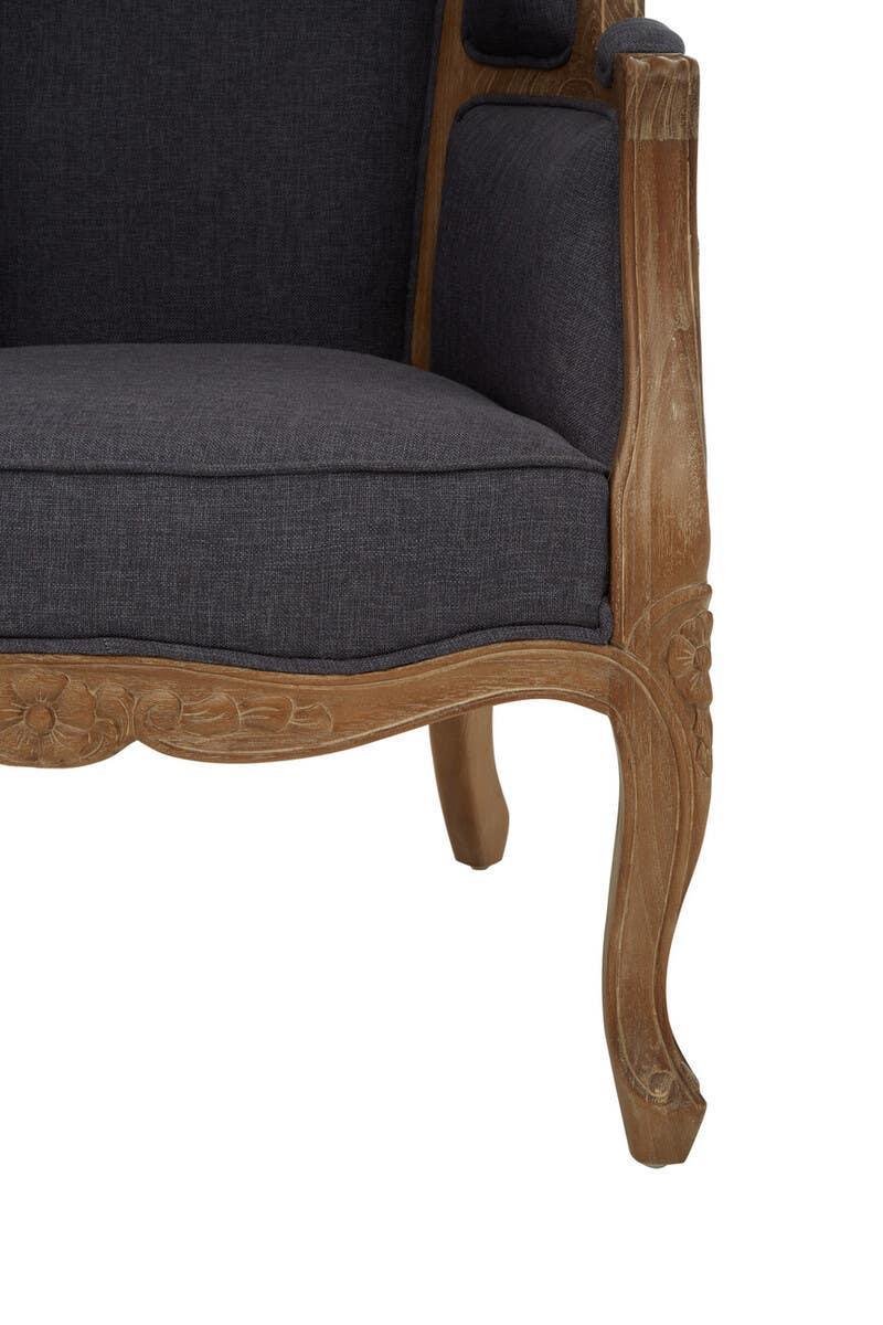Dark grey upholstered armchair with carved wood frame and floral detail, close-up view