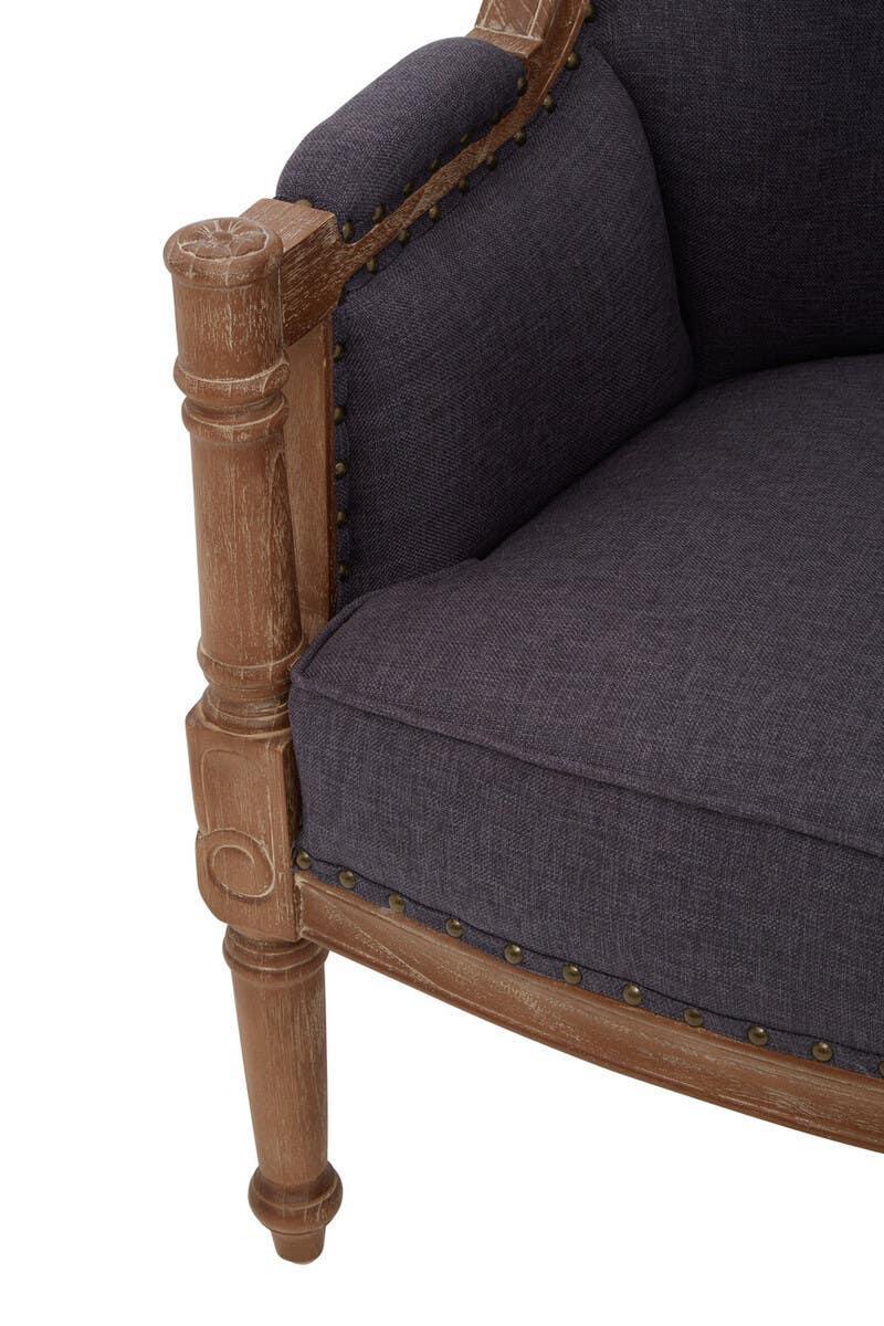 Close view of grey upholstered armchair with wood frame and decorative stud detailing