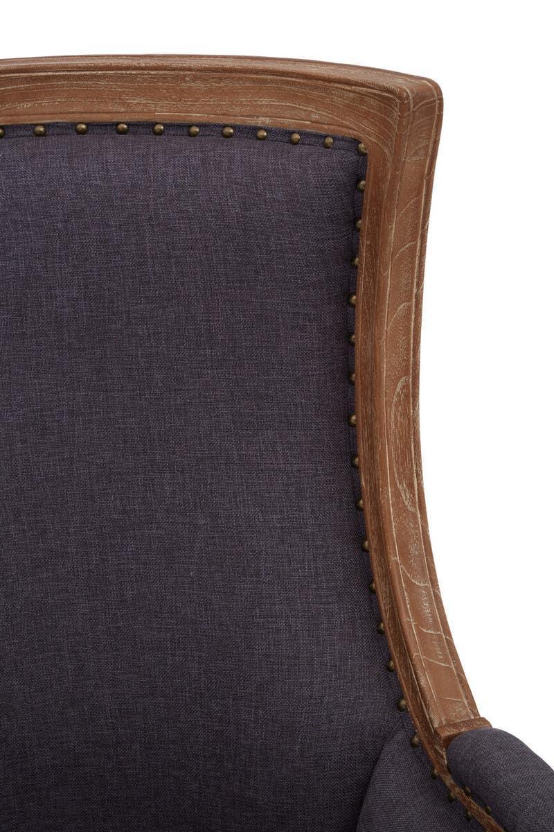 Close-up of dark fabric armchair with wooden frame and antique brass stud detailing