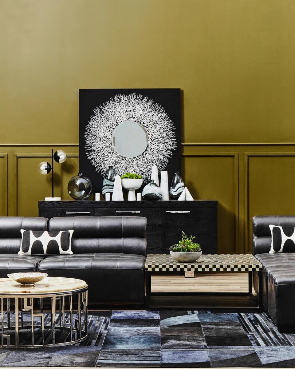 Modern black leather sofa set with patterned cushions and geometric coffee table in living room