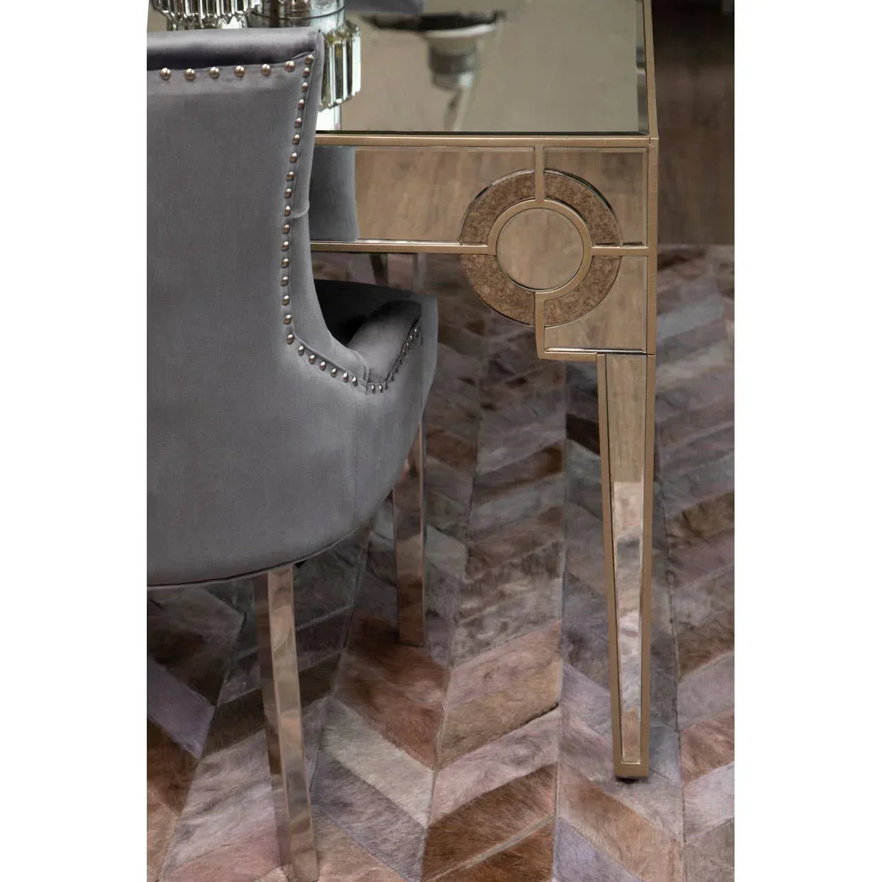 Mirrored dining table with geometric detail and grey velvet studded chair on patterned rug