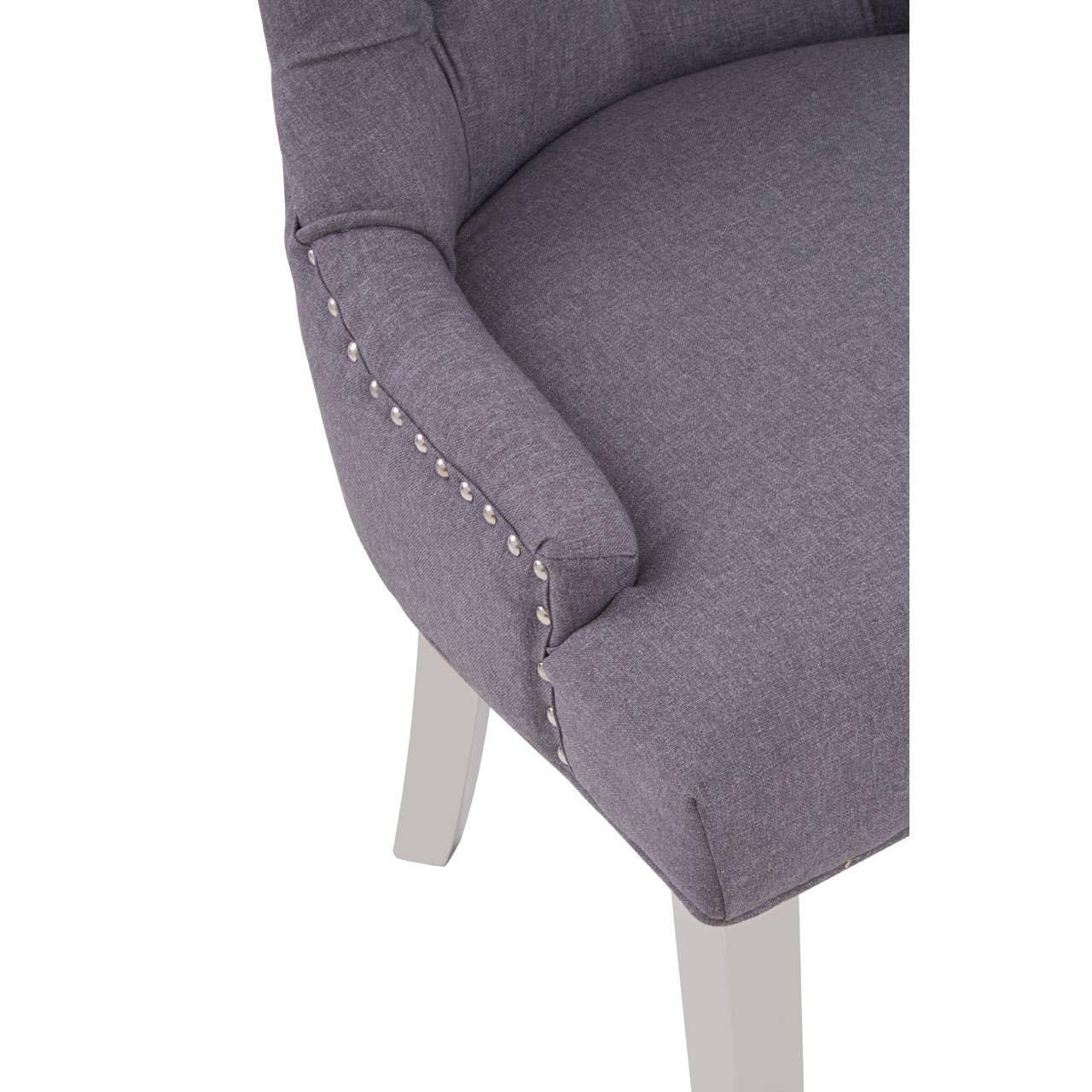 Grey upholstered dining chair with silver stud detailing and white wooden legs
