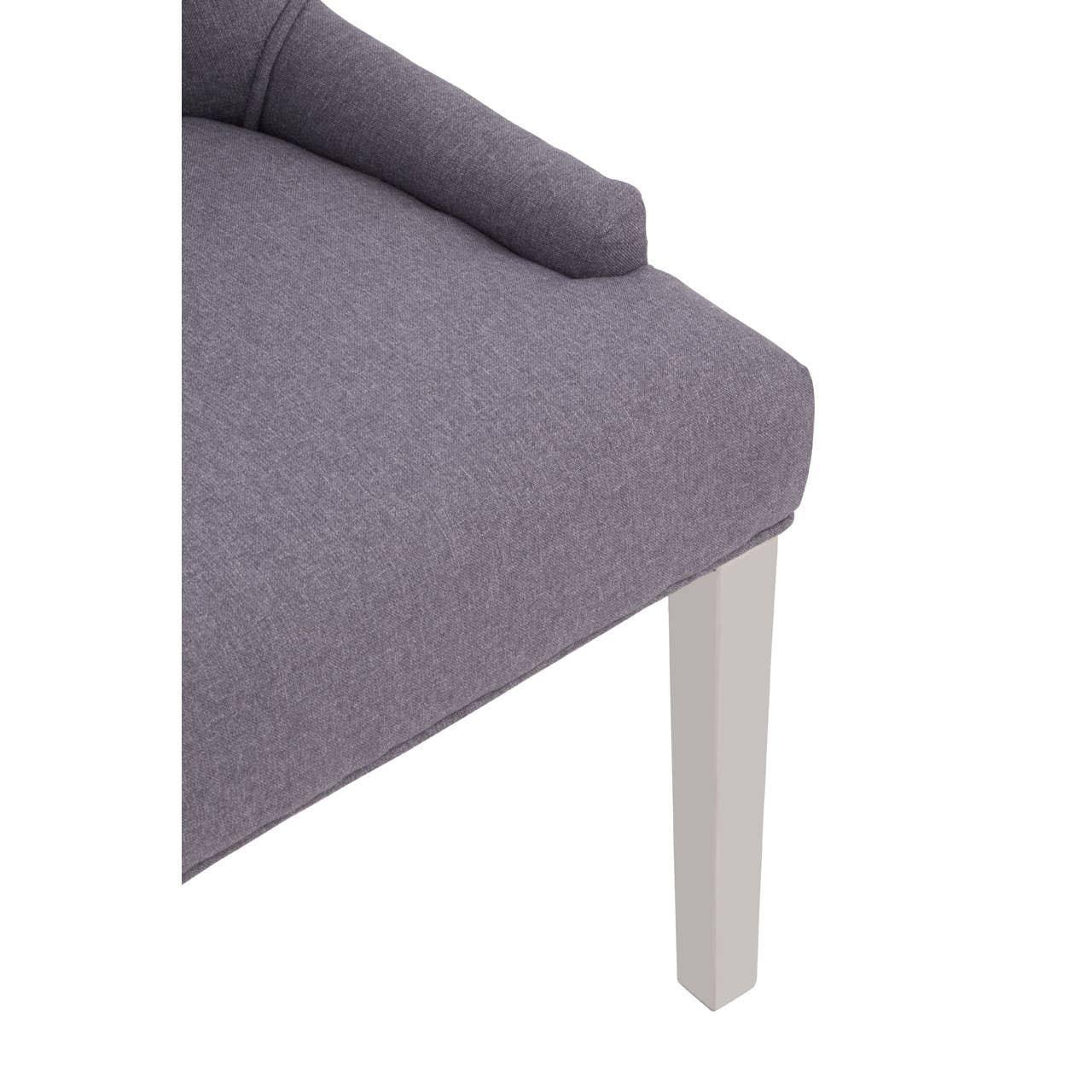 Close-up of grey fabric sofa seat with white wooden leg and round bolster cushion