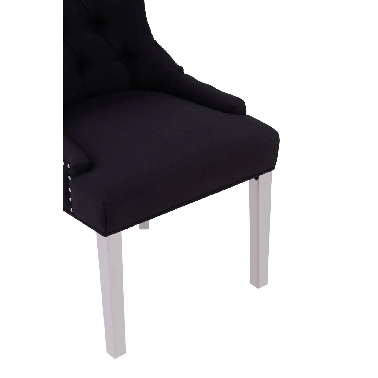 Black upholstered dining chair with tufted back and white wooden legs, side view